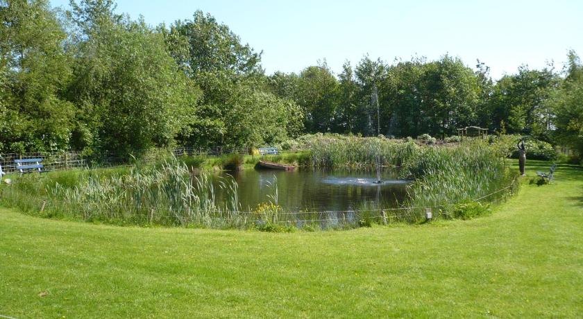 a pond in a grassy area next to a body of water, Apartment Nieuw-Moscou in Hollandscheveld