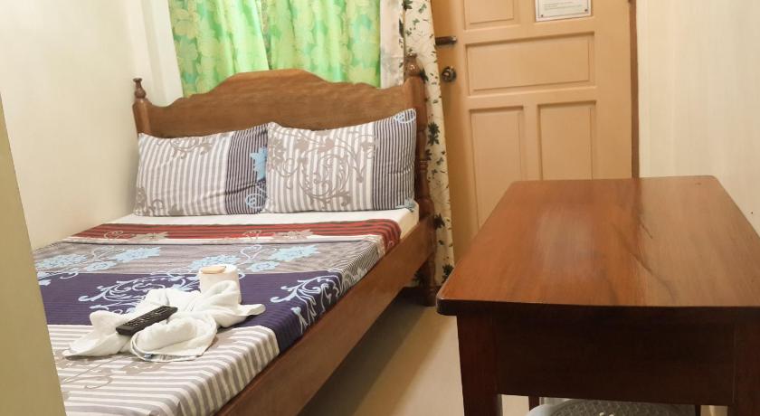 a bed sitting next to a wooden table, Eden Travellers Lodge in Palawan