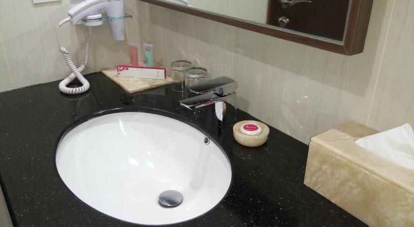 a white sink sitting under a mirror in a bathroom, Orchardz Hotel Bandara in Jakarta