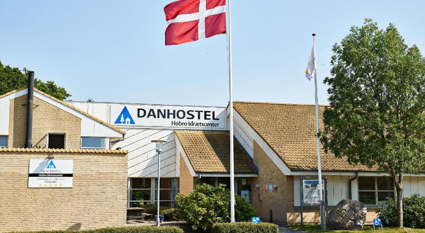 a white building with a flag on top of it, Danhostel Hobro in Hobro