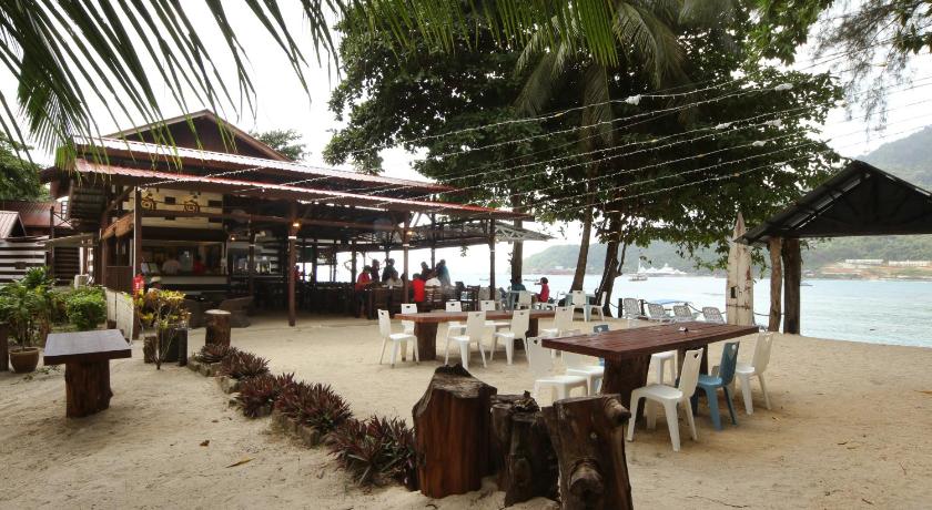 a beach area with chairs, tables and umbrellas, The Barat Perhentian Resort in Perhentian Islands