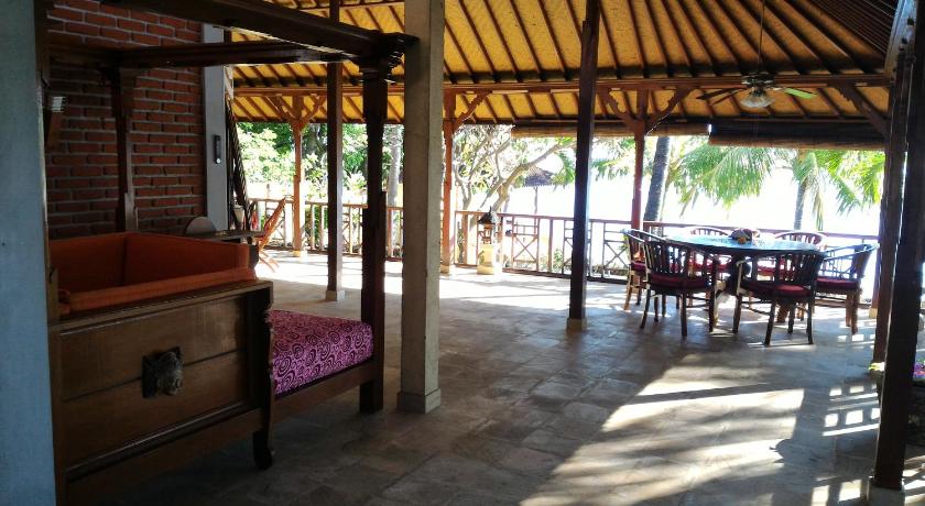 a patio area with chairs, tables, and umbrellas, Teluk Indah Beach & Pool Villa in Bali