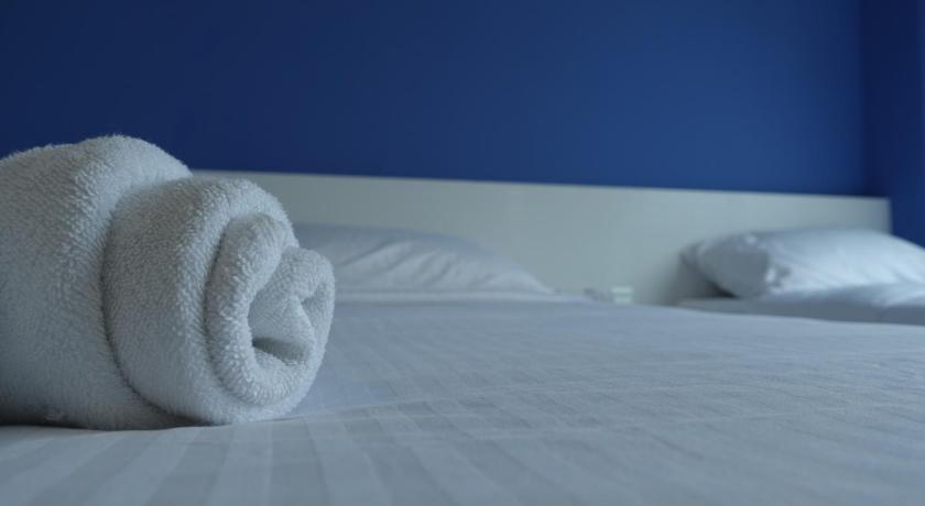 a white towel laying on top of a white bed, Lodge 10 Hotel in Seremban