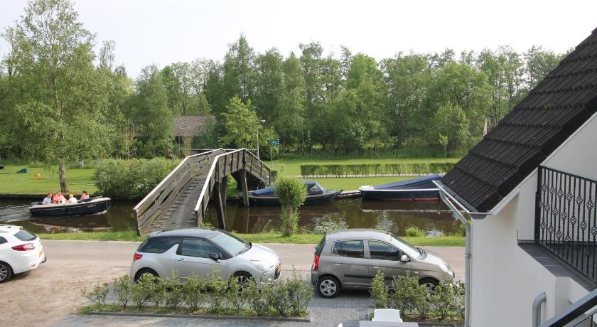 a car parked on the side of a road next to a building, Hotel Giethoorn in Steenwijkerland