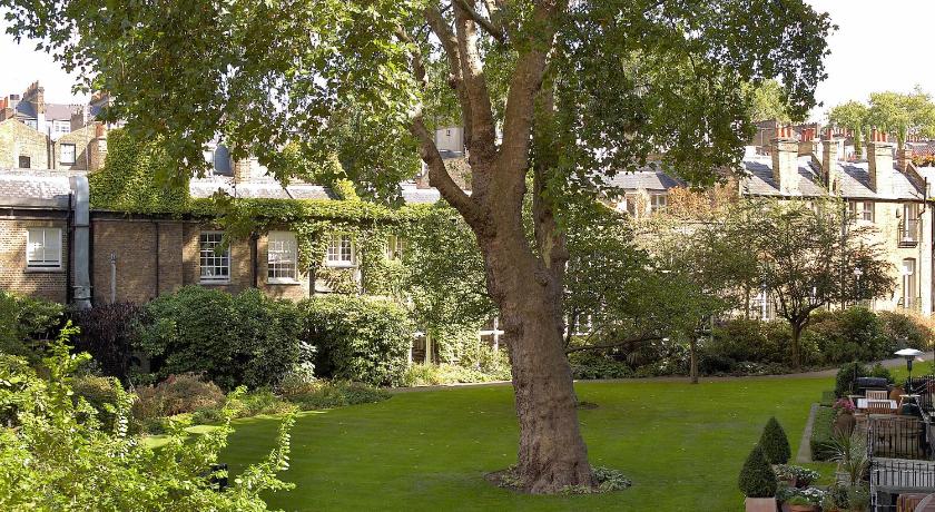 a tree in the middle of a grassy area, Egerton House Hotel in London