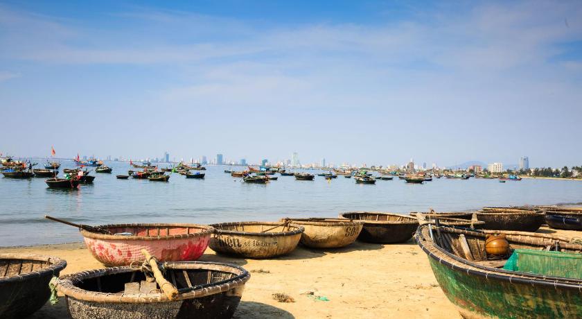 a row of boats sitting on top of a sandy beach, Grand Sea Hotel in Da Nang