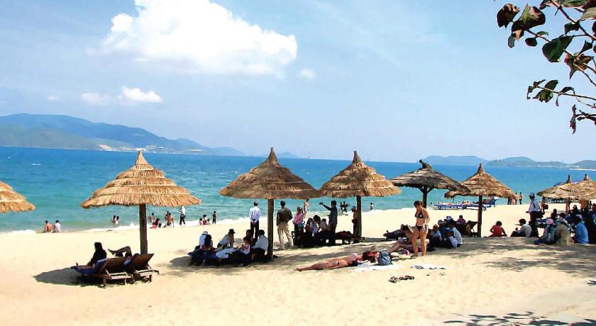 people sitting on top of a sandy beach, Grand Sea Hotel in Da Nang