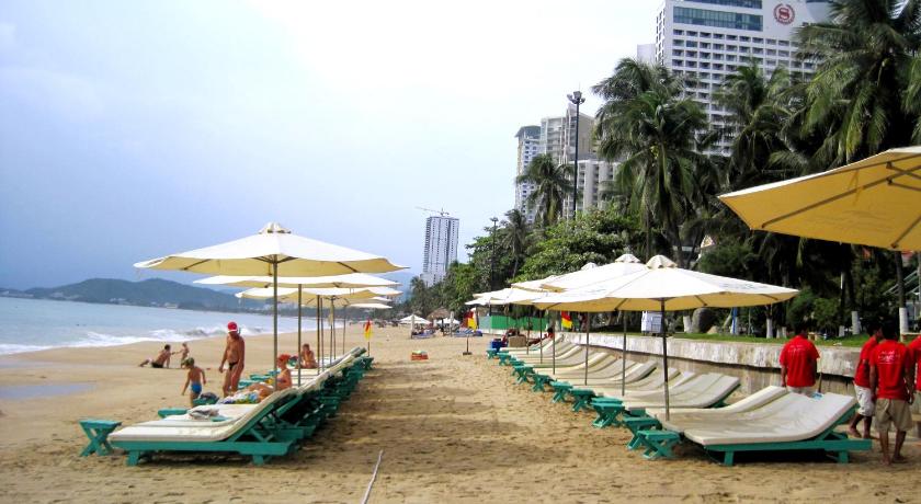 a row of beach chairs sitting on top of a sandy beach, Yasaka Saigon Resort Hotel & Spa in Nha Trang