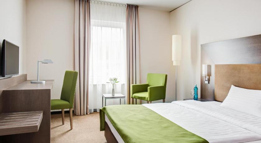 a hotel room with two beds and a television, IntercityHotel Mainz in Mainz