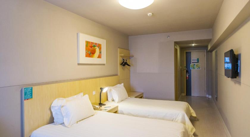a hotel room with two beds and a lamp, Jinjiang Inn Harbin Xinyang Road Airport Bus Station Branch in Harbin