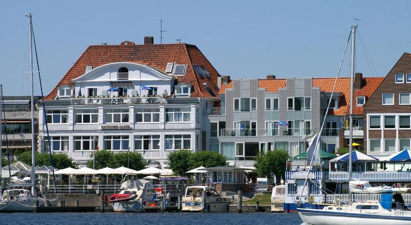 boats are docked at a dock in front of a large building, Hotel Deutscher Kaiser in Lubeck