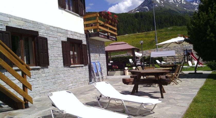 a patio area with chairs, tables and umbrellas, Hotel Chacaril in Gressan