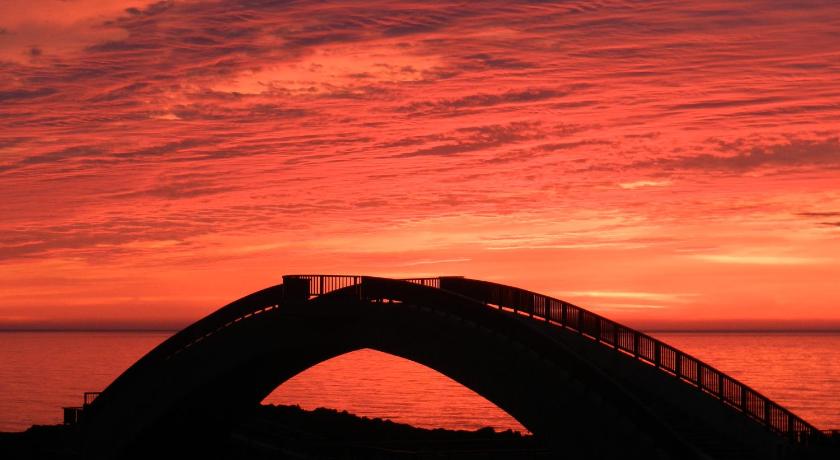 a bridge over a body of water with a sunset, Sado Bellemer Youth Hostel in Sado
