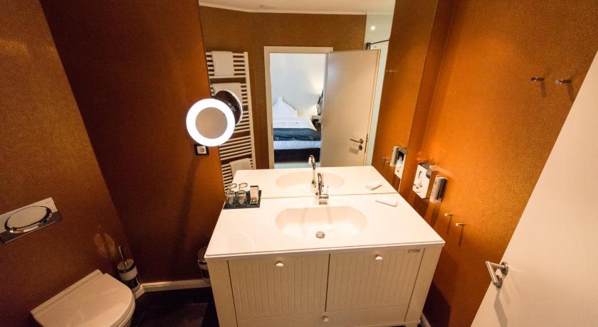 a bathroom with a sink, toilet and mirror, Hotel Business & More in Hamburg