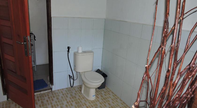a white toilet sitting in a bathroom next to a wall, Batu Kapal Guest House in Timbang Lawan