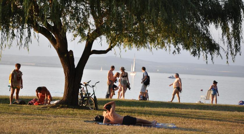 a person laying on a beach next to a body of water, Hotel Melis in Balatonlelle