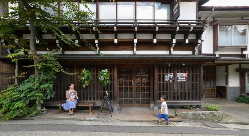 two people sitting on a bench in front of a building, ZEN Hostel in Nagano