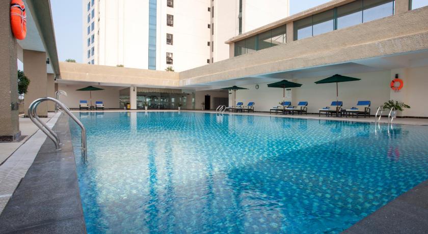 a swimming pool with a blue umbrella in front of a building, Muong Thanh Quang Tri Hotel in Dong Ha (Quang Tri)
