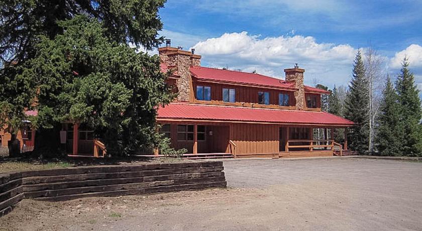 a red brick building with a bench and trees, Arrowhead Mountain Lodge in Cimarron
