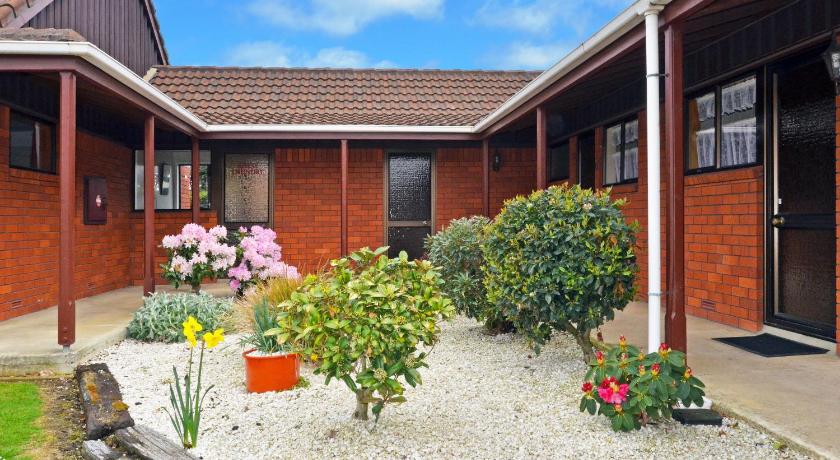 a garden filled with flowers and plants next to a building, Mosgiel Regency Motel in Dunedin