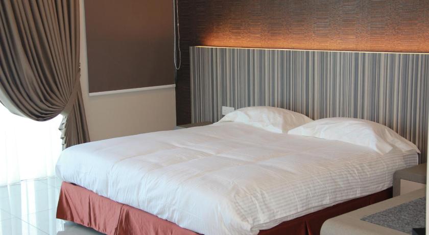 a bed with a white comforter and pillows, Setia Inn Suites Service Residence in Shah Alam