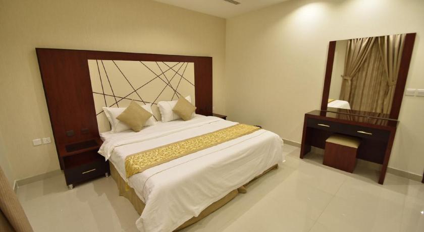 a bedroom with a bed, chair, and nightstand, Abat Suites in Riyadh