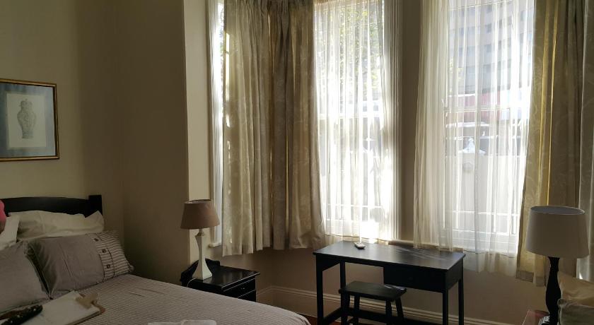 a hotel room with a bed, table and a lamp, Sommersby Guest House in Durban