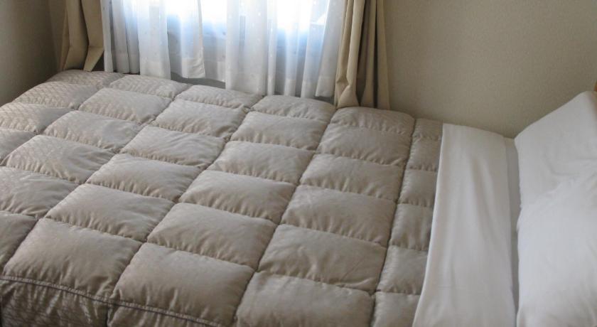 a bed with a white comforter and pillows, Mito Riverside Hotel in Mito