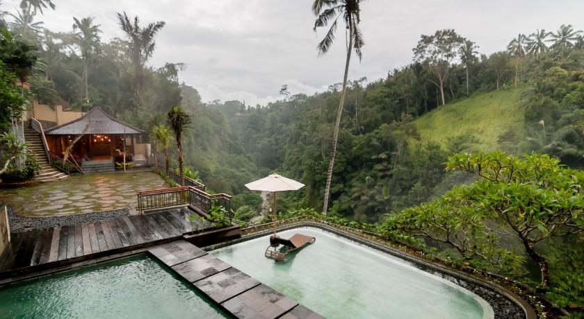 a swimming pool with a pool umbrella and a boat in the water, Ulun Ubud Resort in Bali
