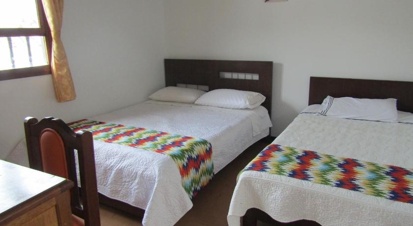 two beds in a room with a white bedspread, La Casona Nunez in Cuitiva