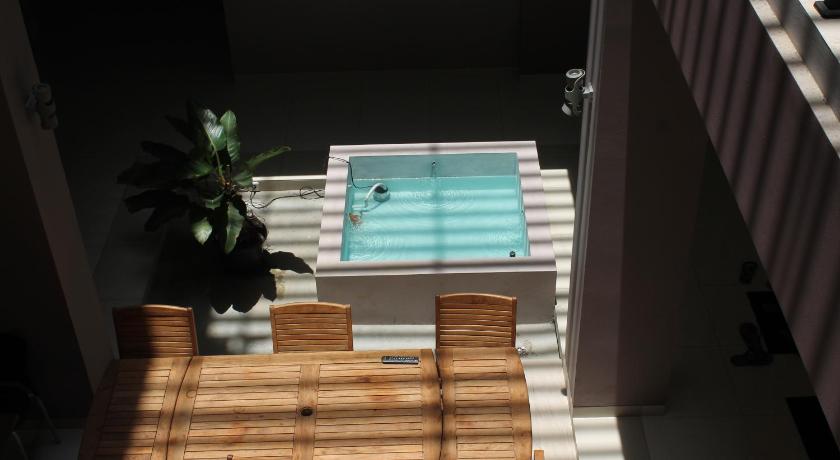 a wooden table topped with a wooden chair next to a pool, Hotel Amalia Malioboro in Yogyakarta