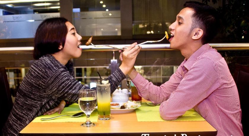 a woman and a man eating food at a restaurant, Green Batara Hotel in Bandung