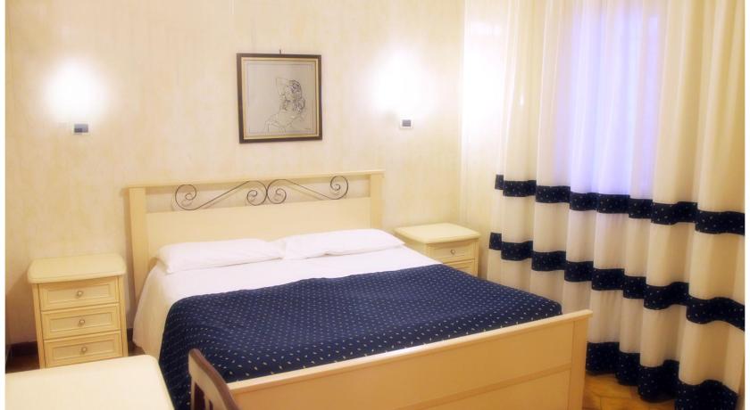 a hotel room with a bed, chair, and nightstand, Hotel Pisani in Taranto