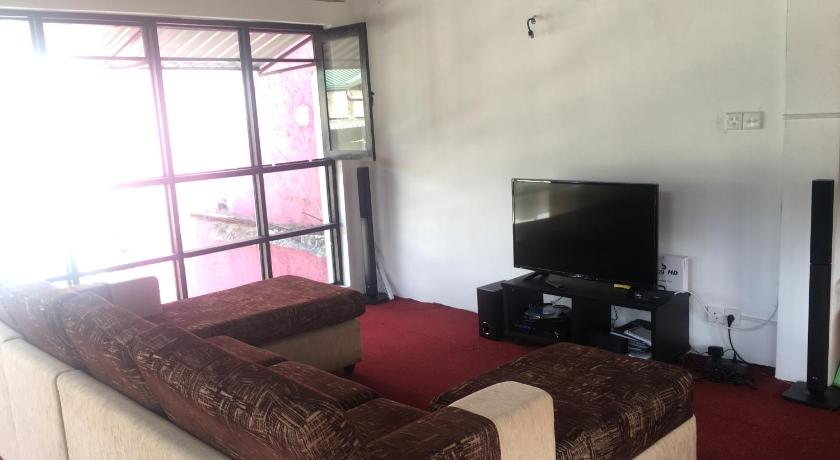 a living room with a couch and a television, Sherwood Lodge in Nuwara Eliya