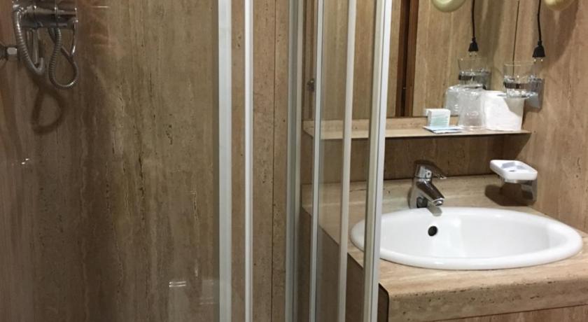 a bathroom with a shower, sink, and toilet, hotel socrate in Lavena Ponte Tresa