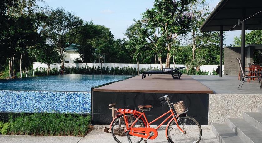 a man riding a bike next to a pool of water, Riverawan Hotel (SHA Plus+) in Chanthaburi