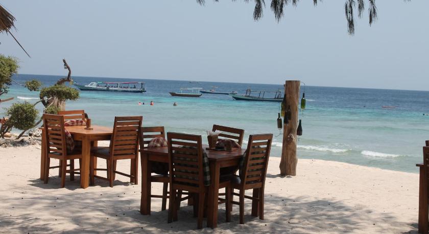 a beach area with chairs, tables, chairs and umbrellas, Melati Cottage in Lombok