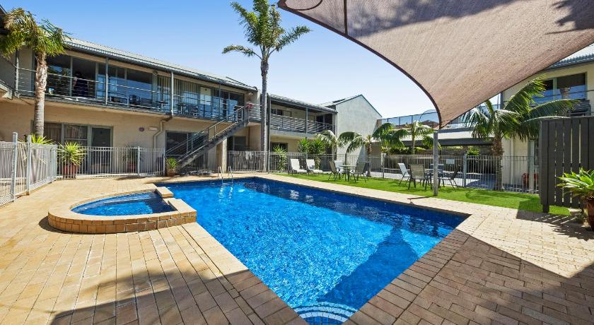 a swimming pool with a blue umbrella on top of it, Moonlight Bay Apartments in Mornington Peninsula