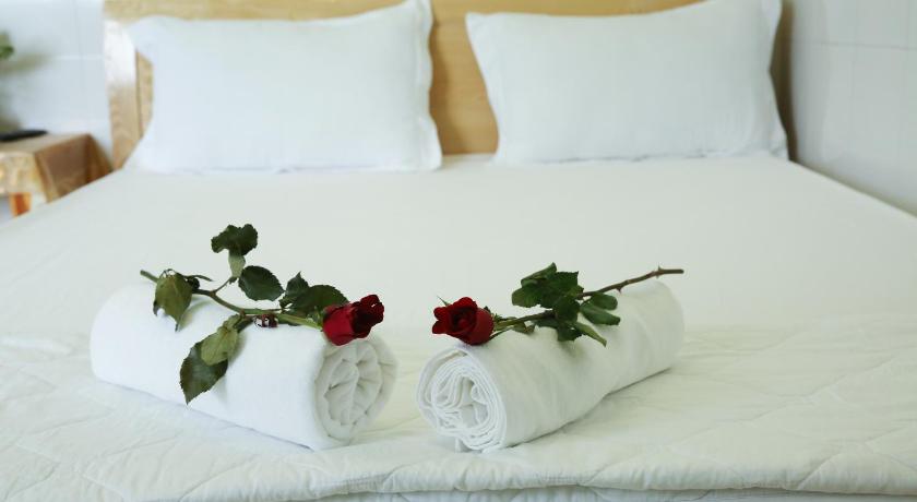 a white vase filled with flowers on top of a bed, Duong Hieu Guesthouse in Phu Quoc Island