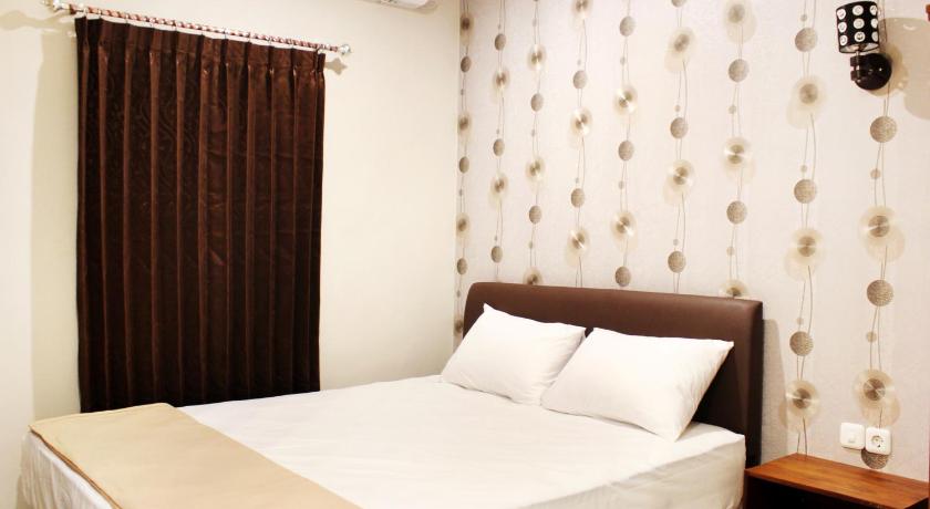 a bed with a white comforter and pillows, House of Dharmawan in Surabaya