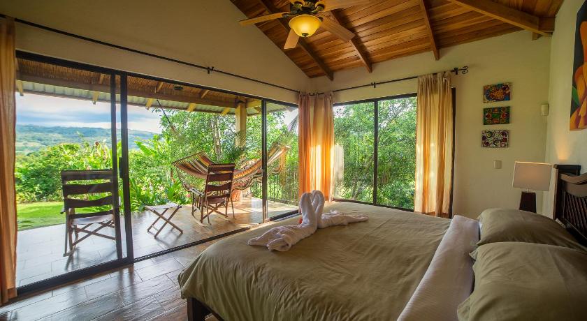 a bedroom with a bed, chair, table and window, La Finca Lodge in La Fortuna