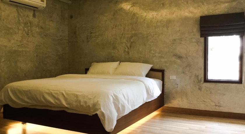 a bedroom with a white bed and a white wall, Nai Suan Inn in Suphan Buri
