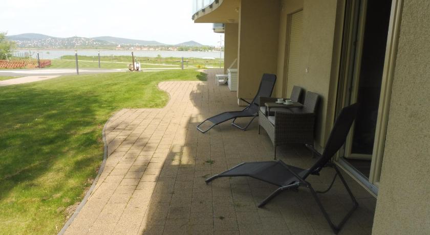 a patio area with chairs, a bench, and a building, Azur Apartman in Velence
