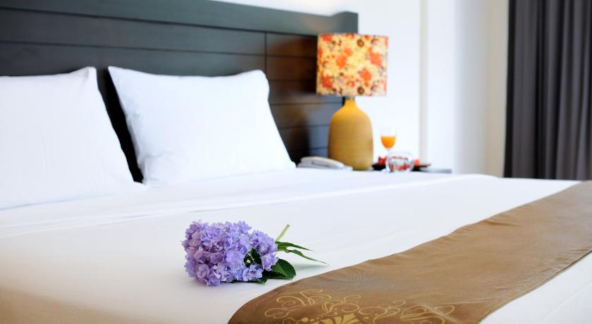 a bouquet of flowers sits on a bed in a hotel room, Kasemsarn Hotel Chanthaburi (SHA Extra Plus) in Chanthaburi