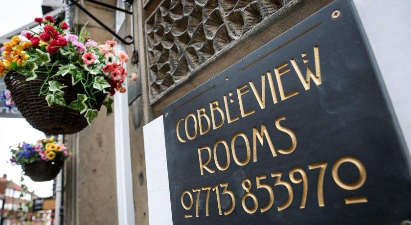 a sign on a building with flowers on it, Cobbleview Rooms in Whitby