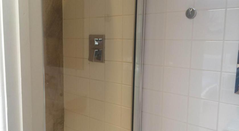 a shower stall with a glass door and a shower curtain, Studio Apartments Camden Town in London