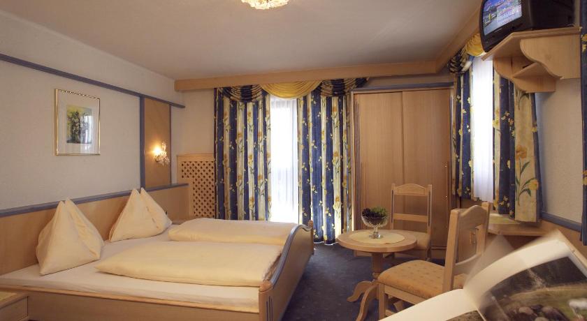 a hotel room with two beds and a television, Ferienanlage Altachhof in Saalbach