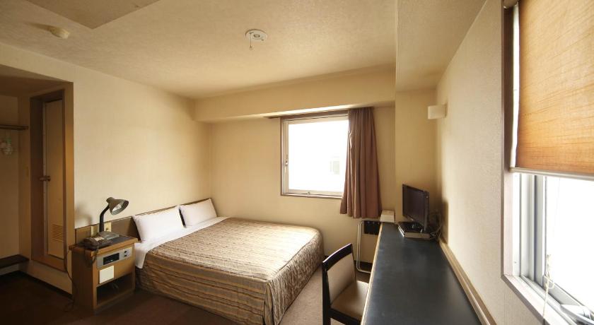 a bedroom with a bed, desk and a window, Isesaki Harvest Hotel in Isesaki