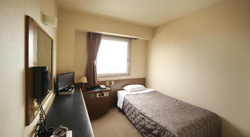 a hotel room with a bed and a desk, Isesaki Harvest Hotel in Isesaki