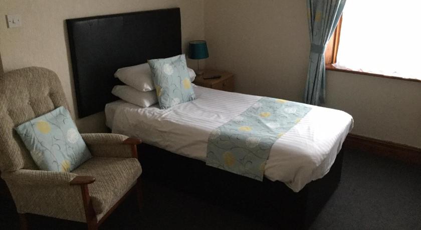 a bedroom with a bed and a chair, Woodlands Guest House in Liverpool